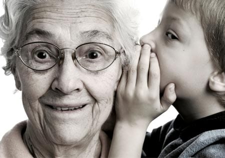 Child whispering in old woman's ear