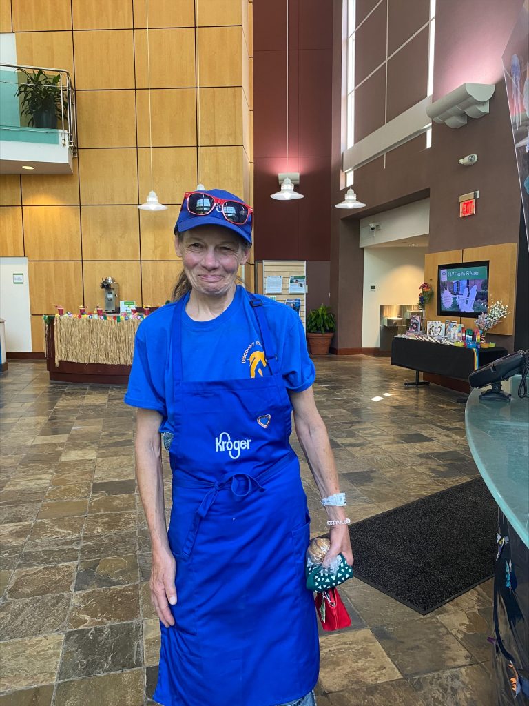Photo of Kat in the library’s atrium wearing her Kroger uniform